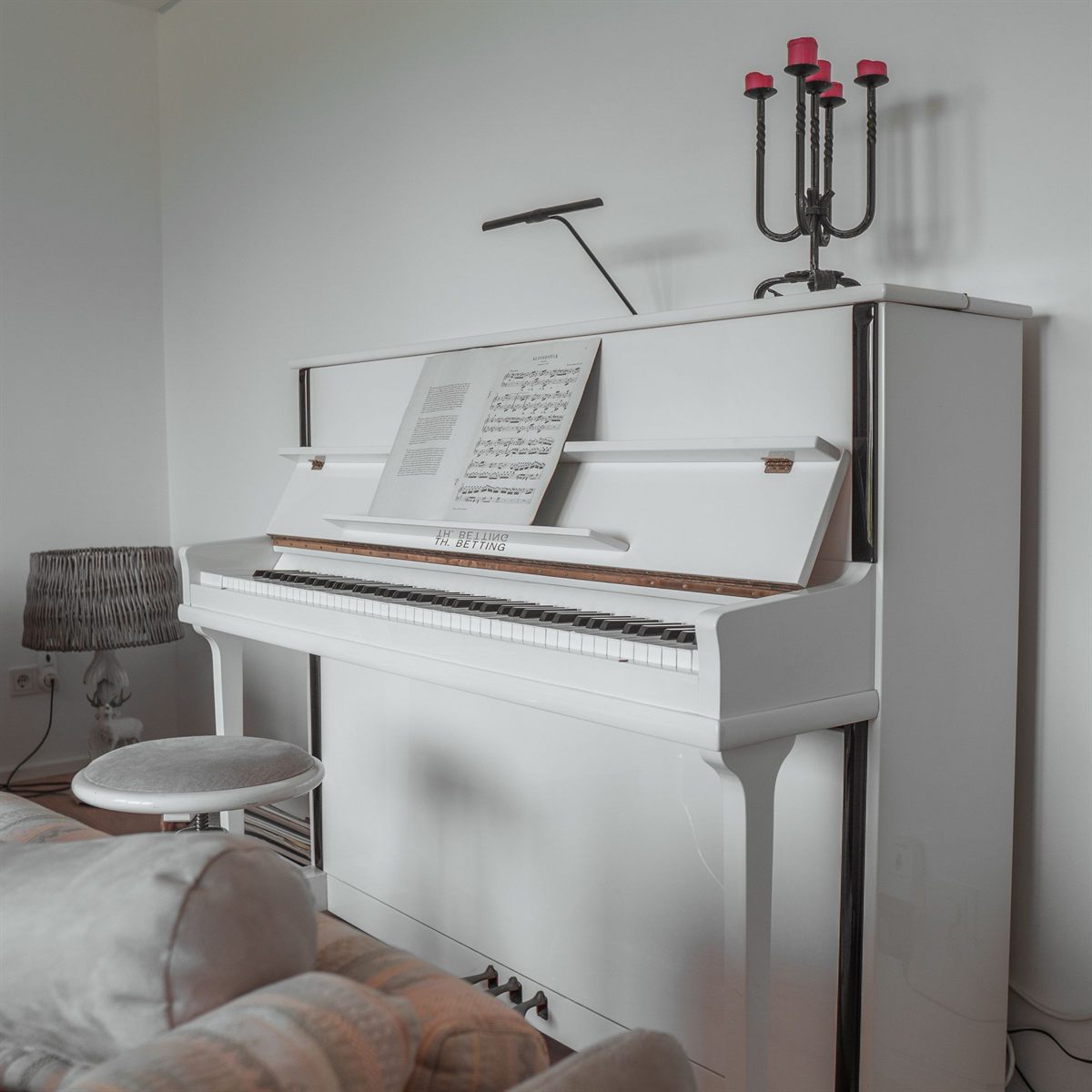 A white upright piano in a pale room, lit from the side