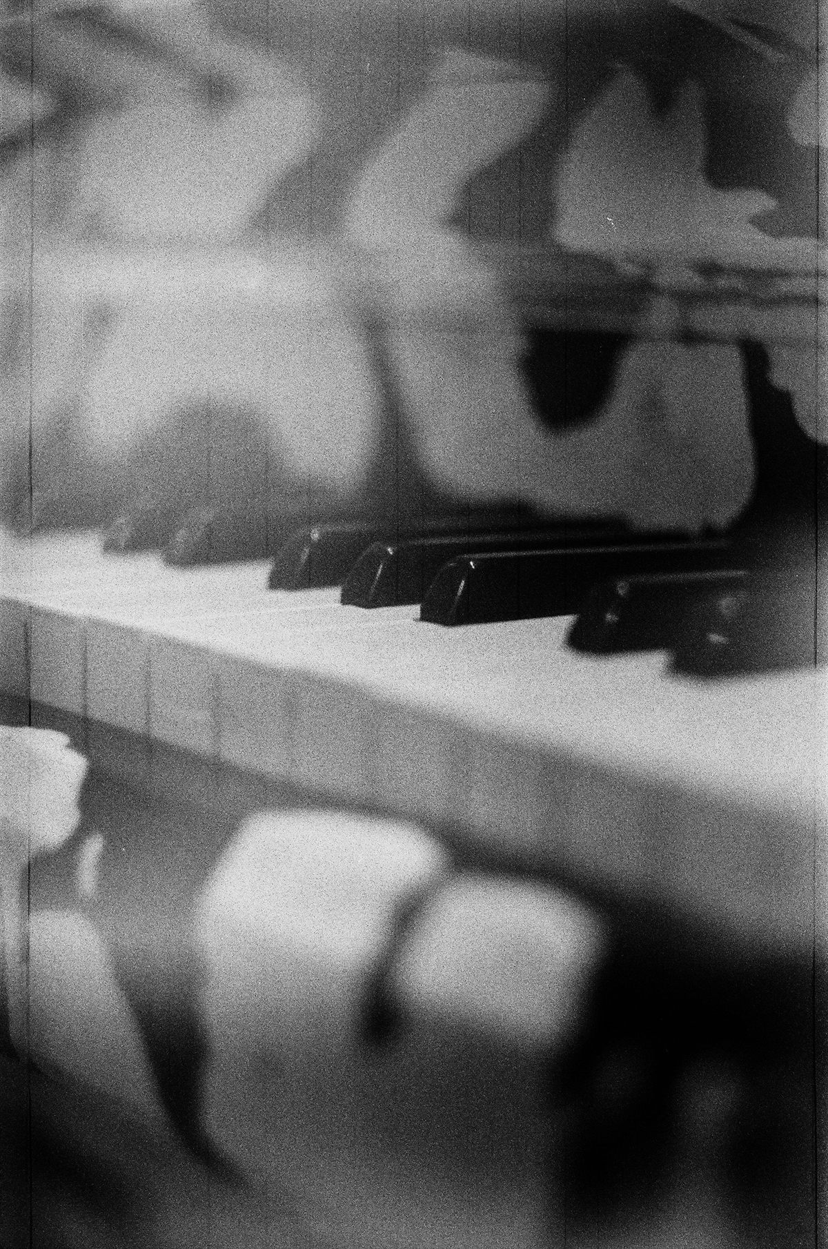 Piano keys softened by fog-like light, in grainy black and white