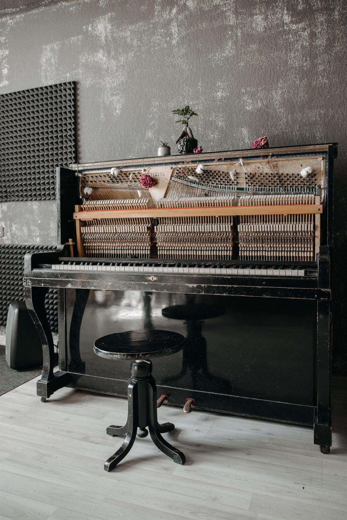 A vintage upright piano and stool in a bare studio