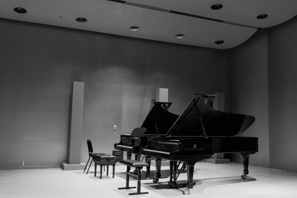 A grand piano alone on the stage of an empty hall, in black and white